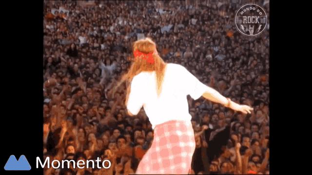 a woman in a pink plaid skirt is dancing in front of a crowd and the word momento is on the bottom right
