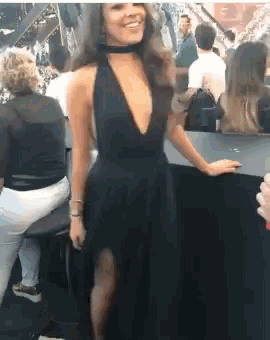 a woman in a black dress with a plunging neckline is smiling