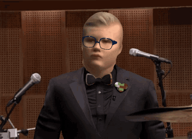 a man wearing glasses and a bow tie adjusts his glasses