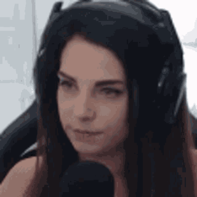 a woman wearing headphones and a microphone is looking at the camera .