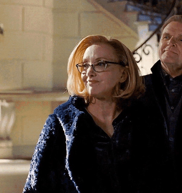 a woman wearing glasses stands next to a man wearing a black shirt