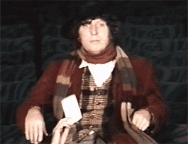 a man in a red jacket and scarf holds a card