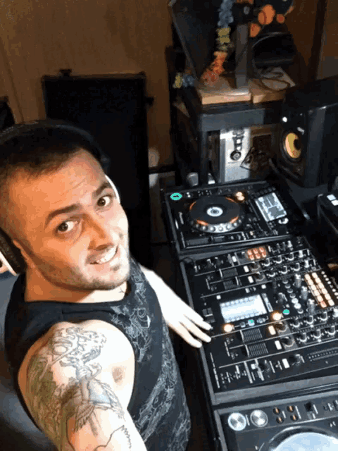 a man with a tattoo on his arm is sitting in front of a dj mixer