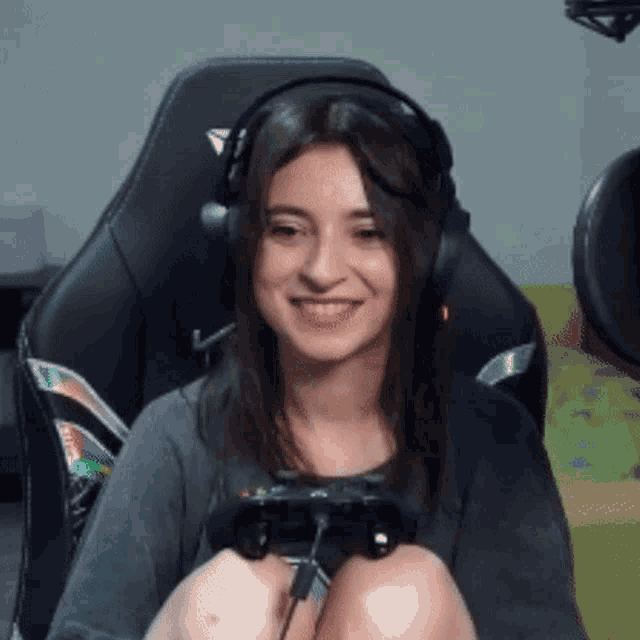 a woman wearing headphones and holding a video game controller is sitting in a chair .