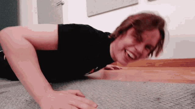 a young man is doing push ups on the floor and smiling