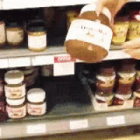 a person is pouring a jar of honey into a jar on a shelf