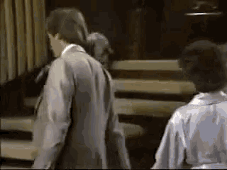 a man in a suit and tie is walking down stairs next to a woman in a robe .