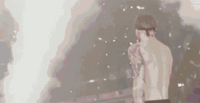 a shirtless man in a baseball cap is standing in front of a cloud of smoke in a dark room .