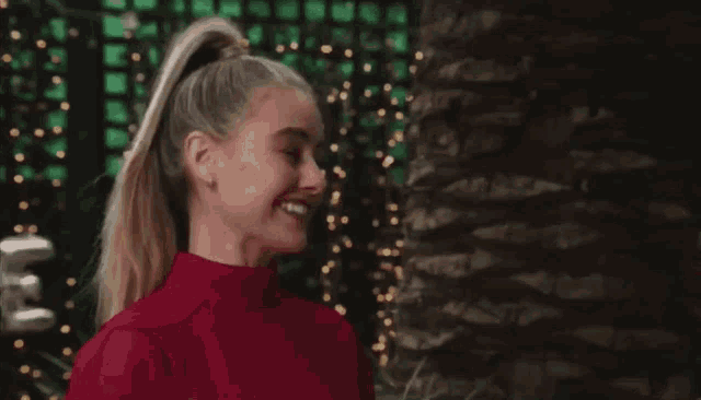 a woman with a ponytail wearing a red top smiles