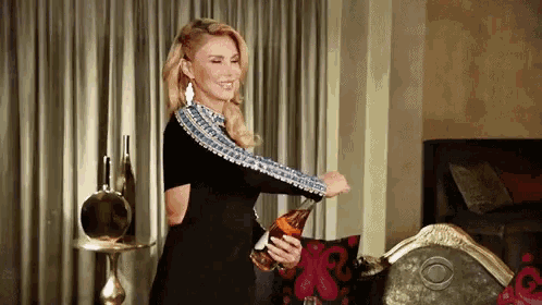 a woman in a black dress is opening a bottle of champagne
