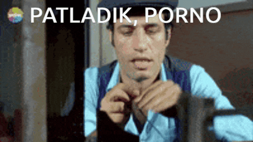 a man in a blue shirt and hat is sitting in front of a sign that says patladik porno