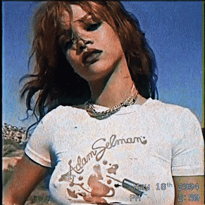 a woman wearing a adam selmani t-shirt stands in front of a blue sky