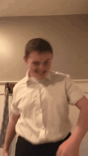 a man in a white shirt and black pants is standing in a bathroom .