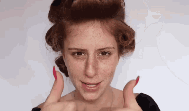a woman with red hair is giving a thumbs up sign