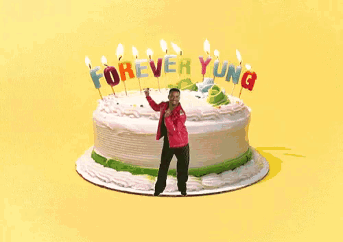 a man is dancing in front of a birthday cake that says forever young