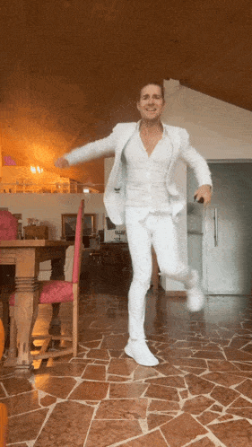 a man in all white is dancing in a living room