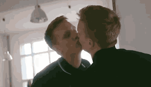 two young men are kissing in front of a mirror .