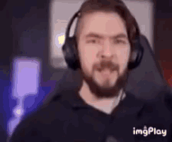a man with a beard wearing headphones and making a funny face .