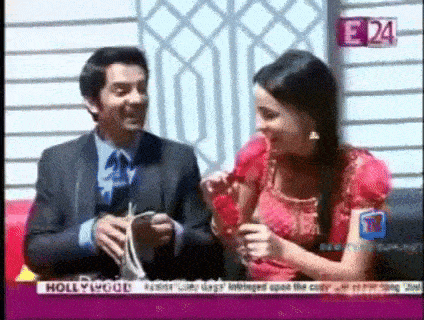 a man and a woman are sitting next to each other on a television screen with hollywood on the bottom