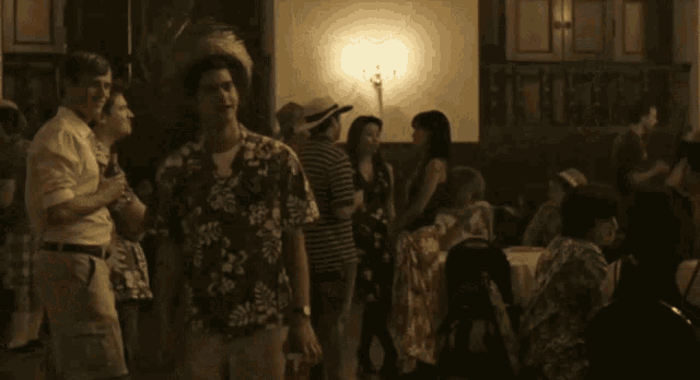 a man wearing a hawaiian shirt and a straw hat is dancing in a room .