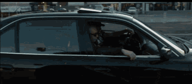a black car is parked on the side of the road in front of a building