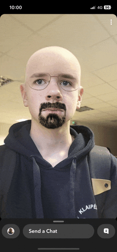 a man with glasses and a fake beard is on a phone screen with a send a chat button