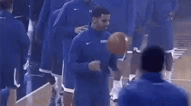 a group of basketball players are standing on a court and talking to each other .