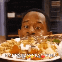 a man is eating a plate of food with a happy thanksgiving message .