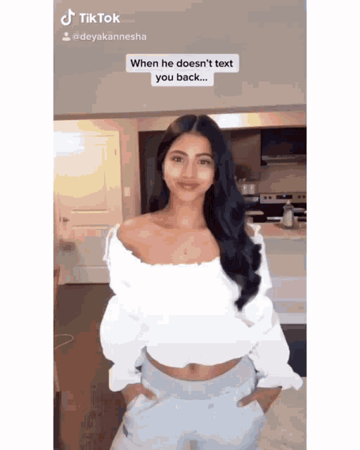a woman in a white off the shoulder top is standing in front of a kitchen