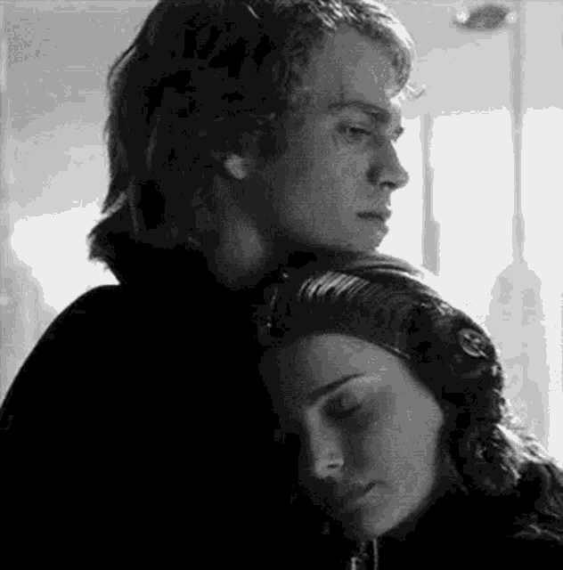 a black and white photo of a man hugging a woman .