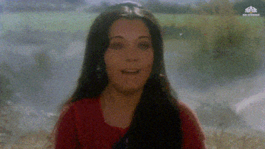 a woman in a red shirt is smiling in front of a sign that says ' mr studios ' on it