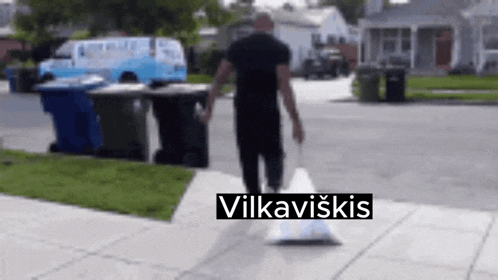 a man is walking down a sidewalk with a bag that says vilkaviskis