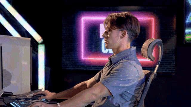 a man is sitting in front of a computer with a neon sign that says ' cpu ' on it