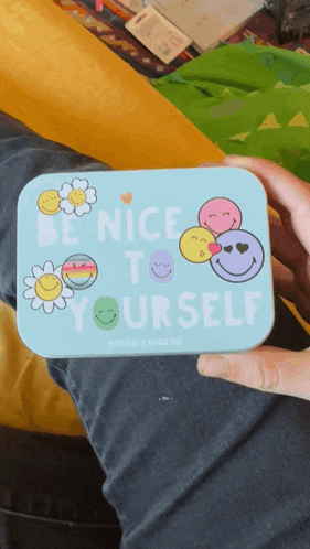someone is holding a blue tin that says be nice to yourself
