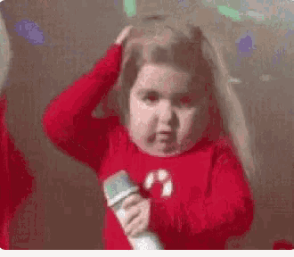 a little girl in a red sweater is holding a microphone in her hand .