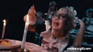 a woman is sitting at a table with a plate of food and a candle in her hand .