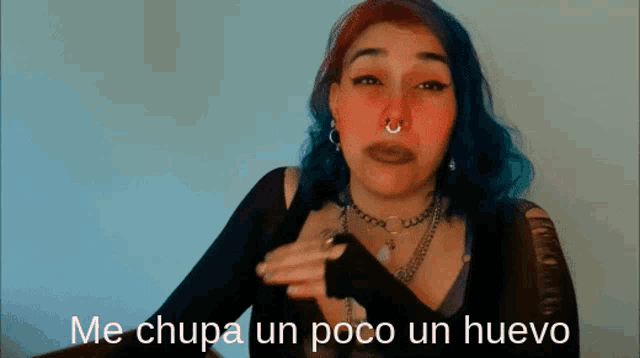 a woman with blue and red hair has the words me chupa un poco un huevo above her