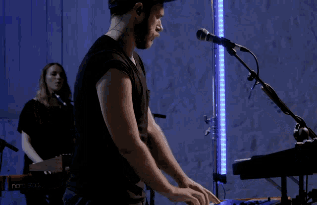 a man playing a keyboard next to a woman playing a guitar