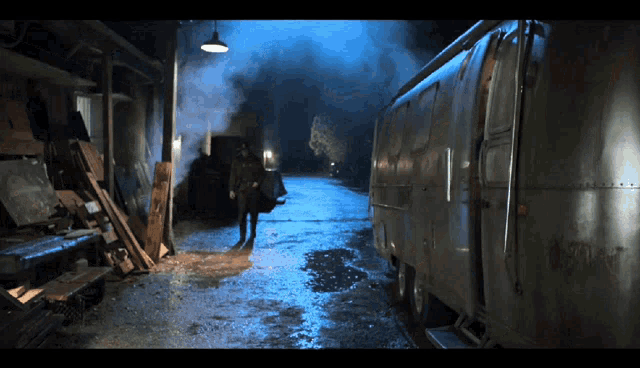 a man standing in a dark alleyway next to a trailer that says ' a ' on it