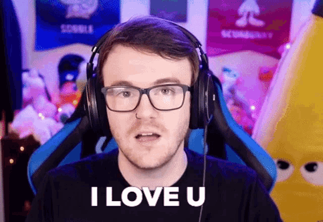 a man wearing glasses and headphones is sitting in a gaming chair and saying `` i love u '' .