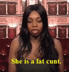 a woman is saying she is a fat cunt in front of a red couch .
