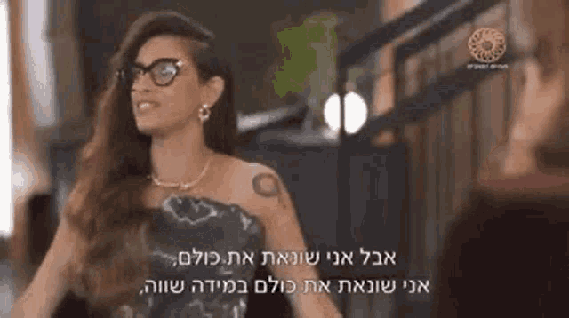 a woman in a black dress and glasses is standing next to a staircase .