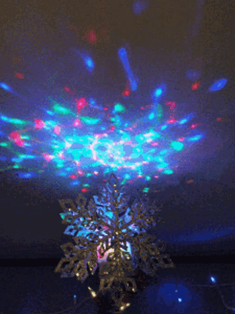 a snowflake on top of a christmas tree with a projection of lights on the ceiling