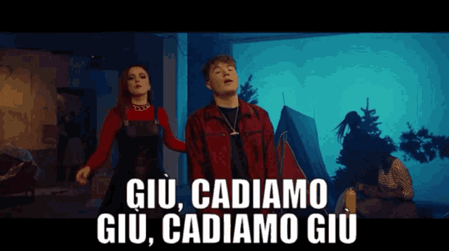 a man and a woman are dancing in front of a tent with the words giù cadiamo giù cadiamo giù