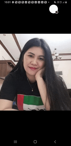 a woman wearing a black shirt with the uae flag on it is smiling