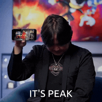 a man holding up a cell phone with the words it 's peak written below him