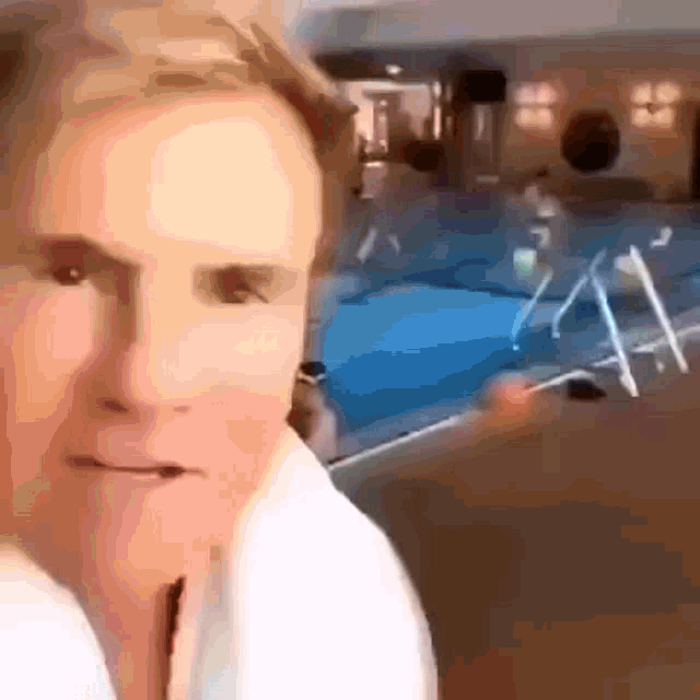 a man is standing in front of a swimming pool looking at the camera
