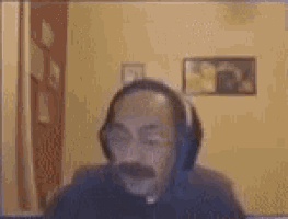 a bald man with a mustache wearing headphones is sitting in front of a computer screen .