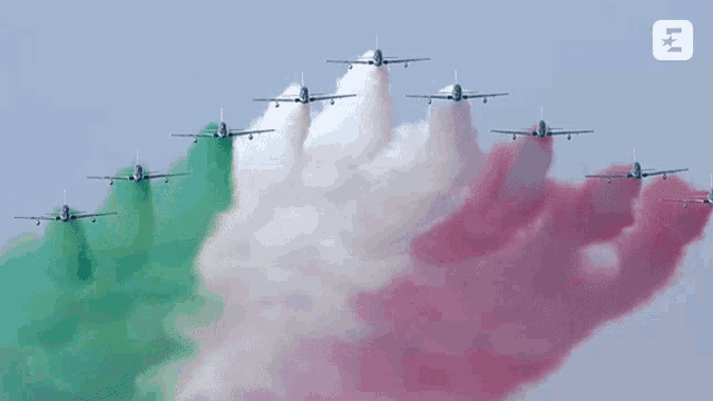 a row of planes with red white and green smoke trails