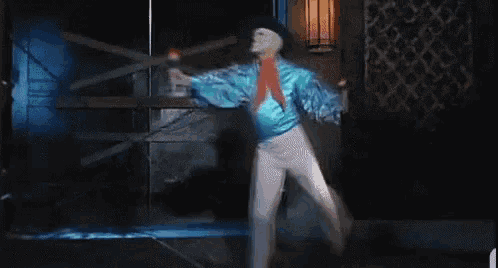 a man in a blue jacket and white pants is holding a microphone and wearing a mask